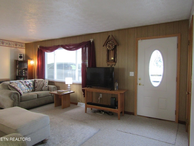 living area with a textured ceiling, carpet floors, wood walls, and baseboards