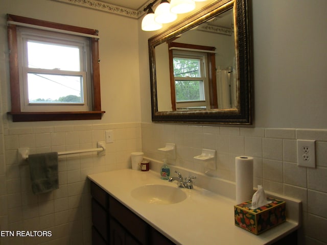 bathroom with a wainscoted wall, tile walls, and vanity