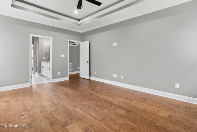 unfurnished bedroom with connected bathroom, ceiling fan, ornamental molding, and a tray ceiling