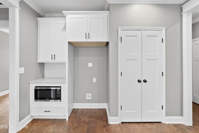 kitchen featuring ornamental molding, stainless steel microwave, white cabinetry, and dark hardwood / wood-style flooring