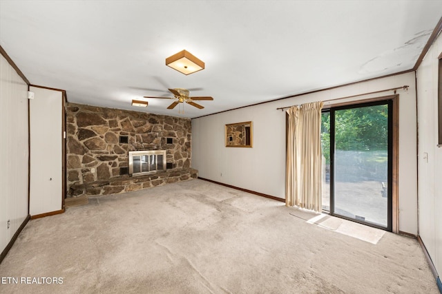 unfurnished living room with ceiling fan, crown molding, light colored carpet, and a stone fireplace