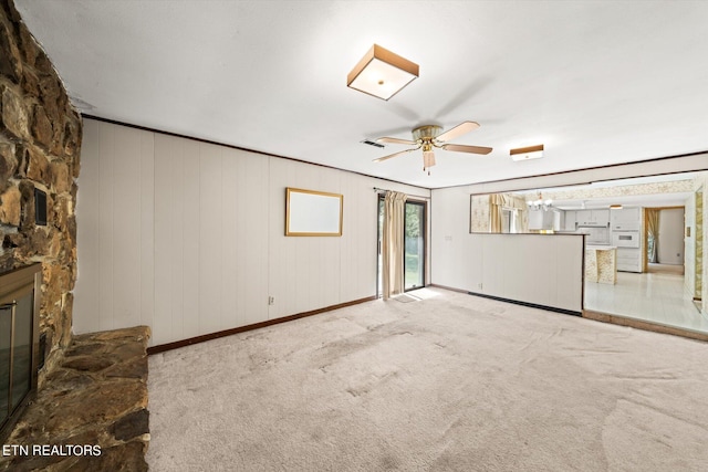 unfurnished living room with ceiling fan, a fireplace, crown molding, and light colored carpet