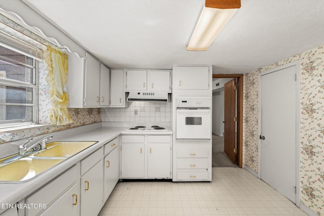 kitchen with decorative backsplash, white cabinets, sink, light tile patterned flooring, and white appliances