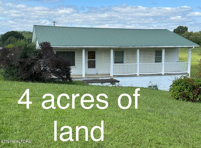 view of front of property with a porch, metal roof, and a front lawn