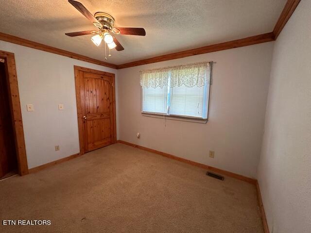 unfurnished bedroom featuring crown molding, a textured ceiling, and ceiling fan