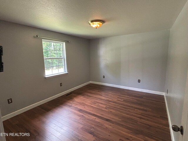 empty room featuring dark wood-type flooring and a textured ceiling