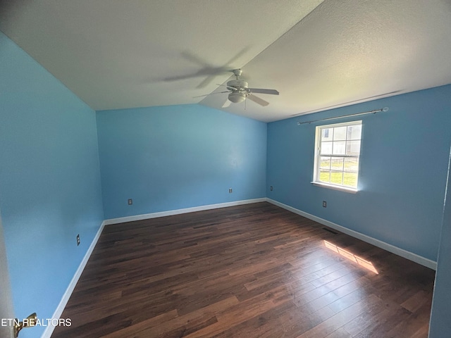 empty room featuring ceiling fan, vaulted ceiling, and dark hardwood / wood-style flooring