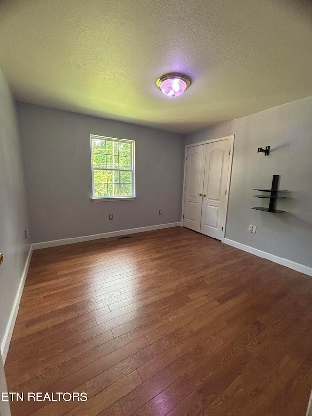 unfurnished bedroom featuring a closet, dark hardwood / wood-style floors, and a textured ceiling