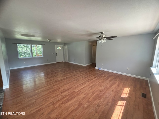 unfurnished living room featuring hardwood / wood-style flooring, ceiling fan, and a textured ceiling