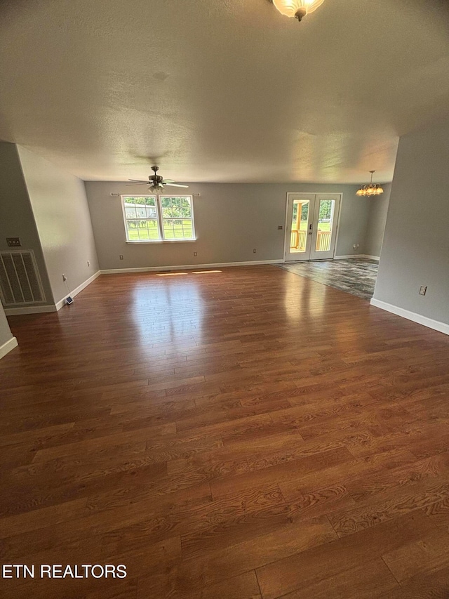 unfurnished room featuring a textured ceiling, ceiling fan with notable chandelier, and dark hardwood / wood-style floors