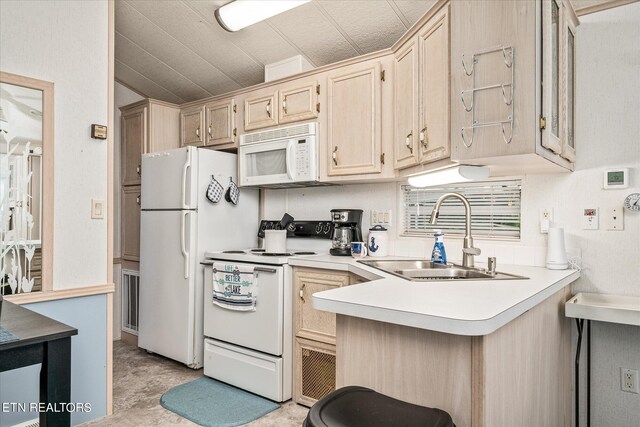 kitchen with white appliances, kitchen peninsula, sink, vaulted ceiling, and light brown cabinets