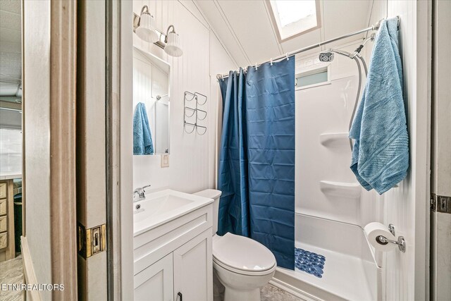 bathroom featuring a skylight, walk in shower, toilet, and vanity