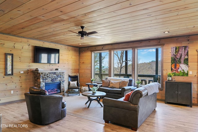 living room featuring a fireplace, light hardwood / wood-style floors, and wooden walls