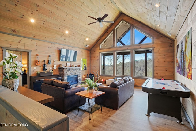 living room featuring ceiling fan, light wood-type flooring, wooden walls, wooden ceiling, and a fireplace