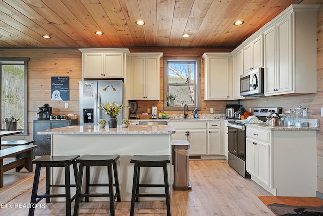 kitchen with light wood-type flooring, appliances with stainless steel finishes, plenty of natural light, and a kitchen island