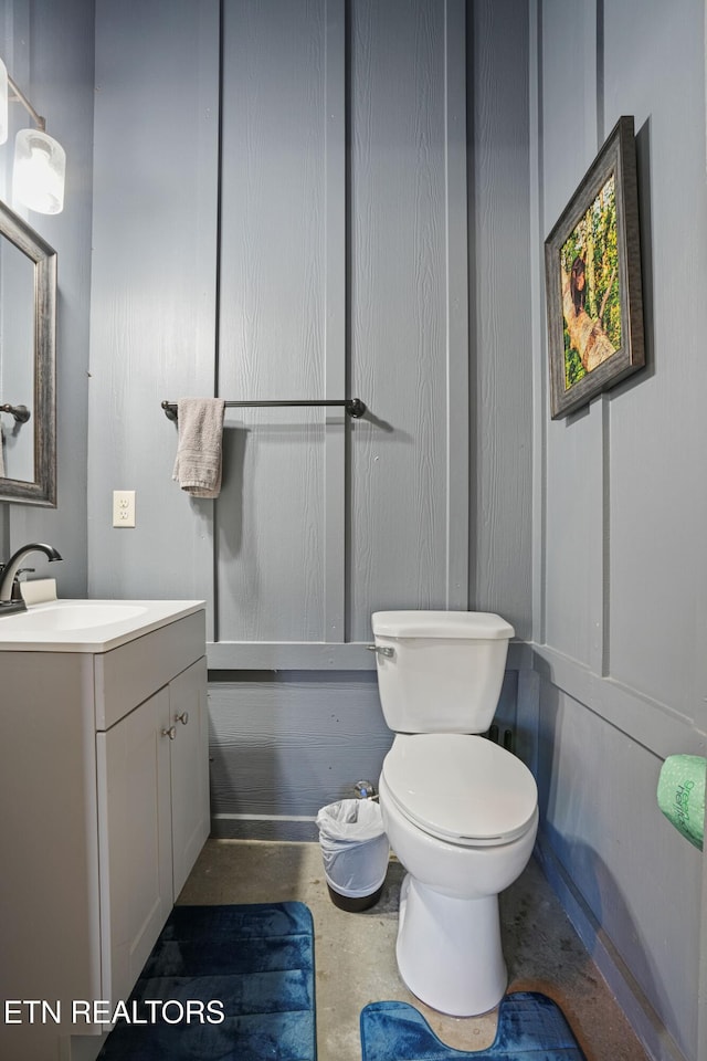 bathroom featuring toilet, vanity, and concrete flooring