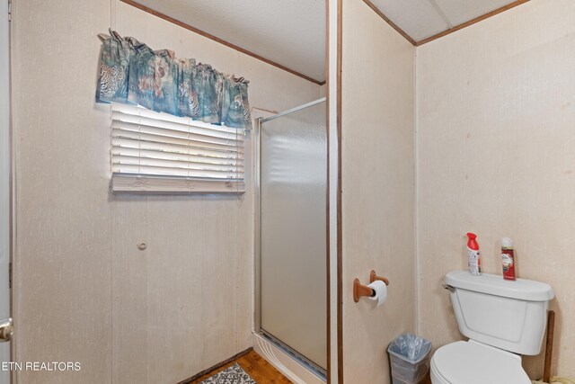 bathroom with hardwood / wood-style floors, toilet, walk in shower, and ornamental molding