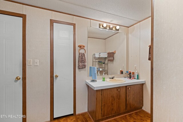 bathroom with hardwood / wood-style floors, a textured ceiling, and vanity