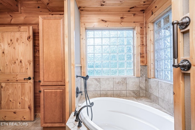 bathroom featuring wood walls and tiled bath