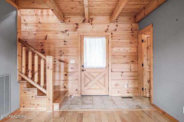 interior space featuring light wood-type flooring, wood ceiling, beamed ceiling, and wood walls