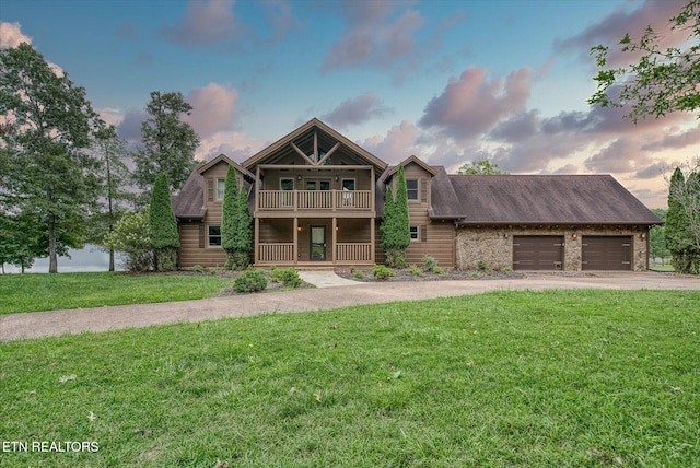 view of front of house featuring a garage, a balcony, and a lawn