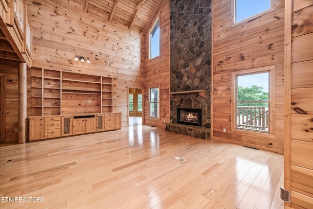 unfurnished living room with a fireplace, light wood-type flooring, high vaulted ceiling, and wooden ceiling