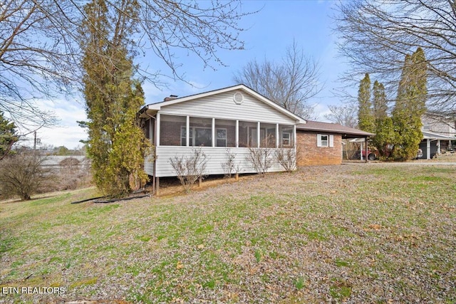 rear view of property with a lawn, a sunroom, and a carport