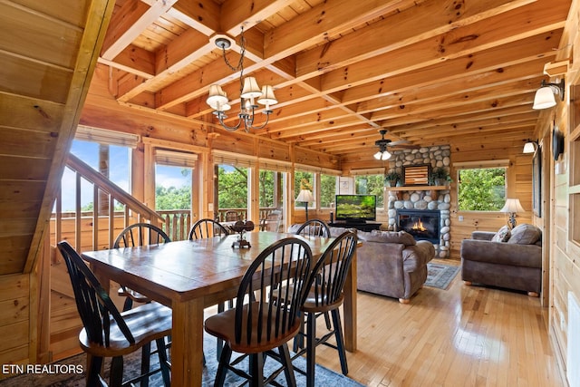 dining room featuring light wood-style flooring, wood walls, wood ceiling, and a healthy amount of sunlight