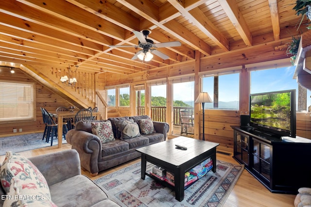 living area with light wood-style flooring, wooden walls, beam ceiling, ceiling fan with notable chandelier, and wood ceiling