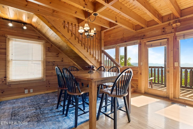 dining space featuring wood ceiling, wood walls, a chandelier, and visible vents