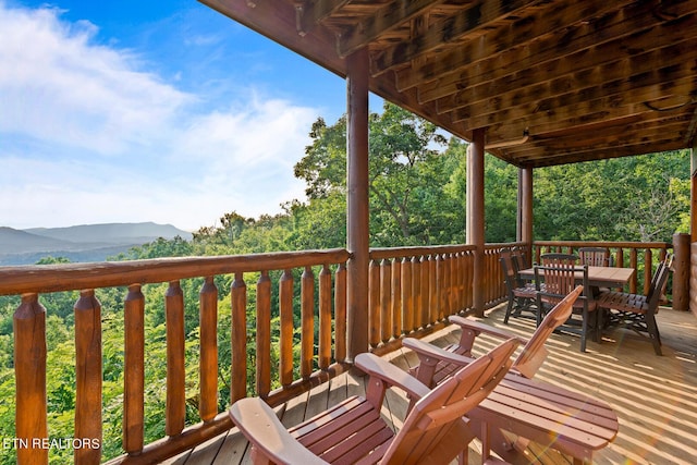 wooden terrace featuring a mountain view and outdoor dining space
