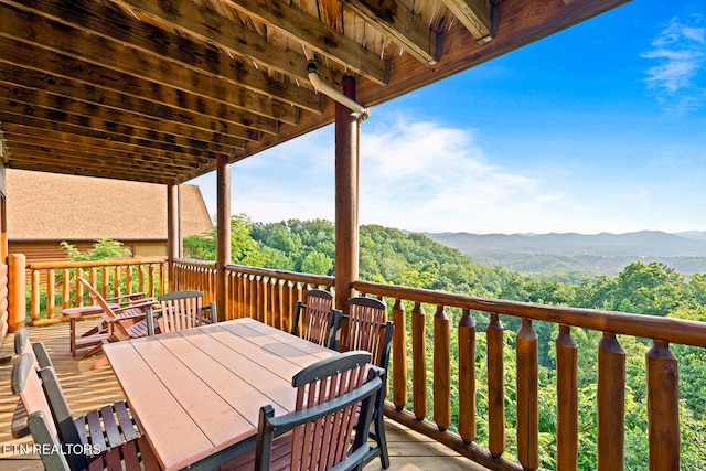 wooden deck featuring outdoor dining space and a forest view