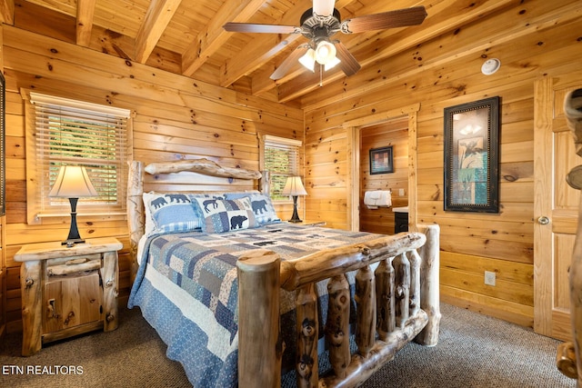 bedroom with carpet, wood walls, and beamed ceiling