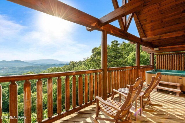 wooden deck featuring a hot tub and a mountain view