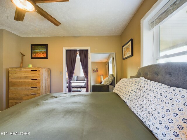 bedroom with ceiling fan, a textured ceiling, and multiple windows