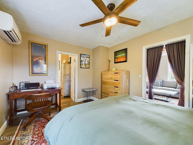 bedroom with ceiling fan, an AC wall unit, hardwood / wood-style floors, ensuite bathroom, and a textured ceiling