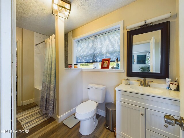 full bathroom featuring hardwood / wood-style flooring, toilet, a textured ceiling, and vanity