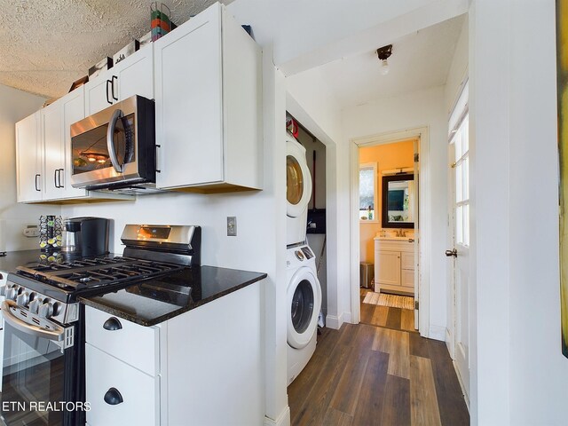 laundry area featuring a textured ceiling, stacked washer and dryer, and dark hardwood / wood-style flooring