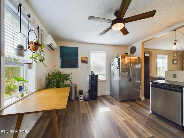 interior space featuring stainless steel appliances, a healthy amount of sunlight, dark hardwood / wood-style flooring, and a wall unit AC