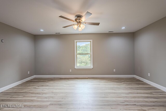 spare room featuring a ceiling fan, light wood-type flooring, and baseboards