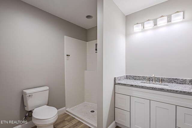 bathroom with a shower, wood-type flooring, vanity, and toilet