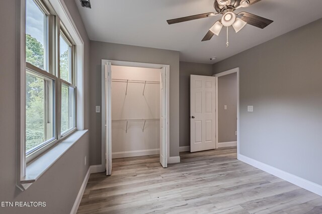 unfurnished bedroom featuring a closet, light hardwood / wood-style floors, and multiple windows