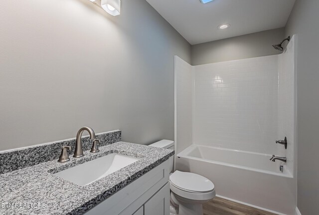 full bathroom featuring hardwood / wood-style flooring, vanity, shower / bathtub combination, and toilet