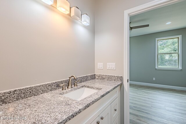 bathroom with hardwood / wood-style flooring, ceiling fan, and vanity