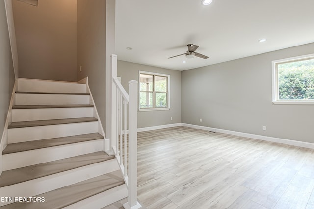 stairway featuring recessed lighting, plenty of natural light, wood finished floors, and baseboards