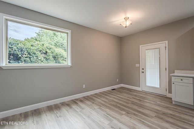 unfurnished room with baseboards and light wood-style floors