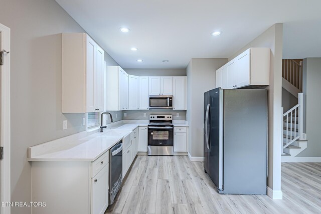 kitchen featuring white cabinetry, stainless steel appliances, light countertops, and light wood-style floors