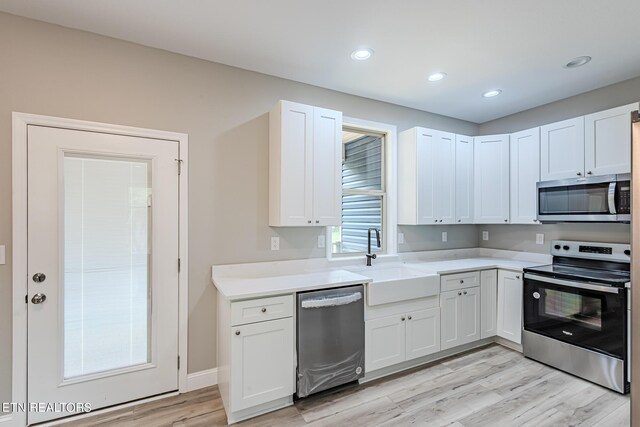 kitchen with stainless steel appliances, light hardwood / wood-style floors, sink, and white cabinets