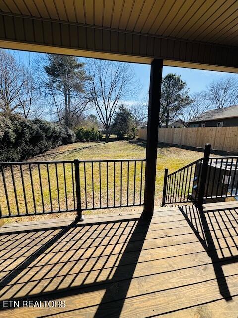 wooden terrace featuring a yard and fence