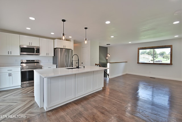 kitchen with sink, stainless steel appliances, white cabinetry, and an island with sink